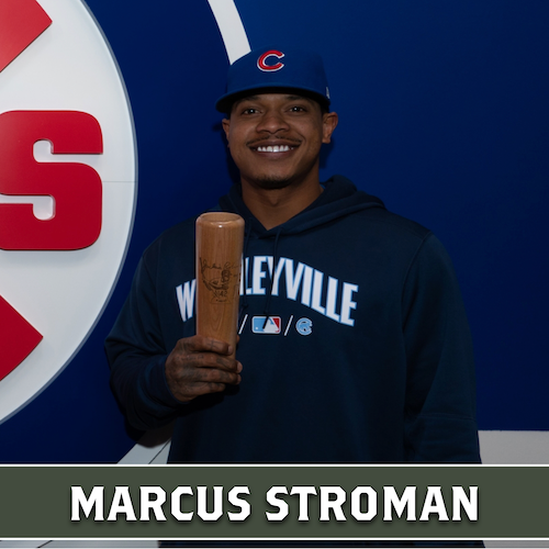 Marcus Stroman holding a wooden Dugout Mugs baseball bat mug while wearing a Chicago Cubs cap.