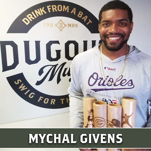 Mychal Givens wearing an Orioles shirt behind a collection of wooden Dugout Mugs baseball bat mugs.