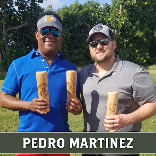 Pedro Martinez posing outdoors beside another man, both holding wooden Dugout Mugs baseball bat mugs.