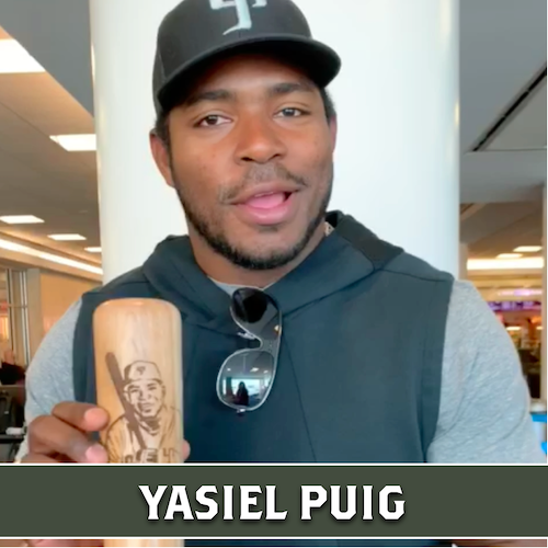 Yasiel Puig holding a wooden Dugout Mugs baseball bat mug engraved with a portrait.